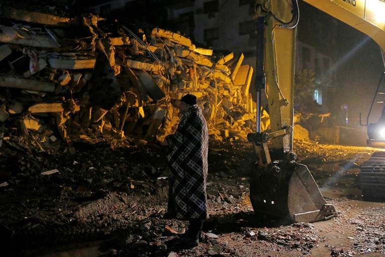 地震で倒壊した建物の前に立ち尽くす男性＝トルコ・オスマニエ県/Dilara Senkaya/Reuters