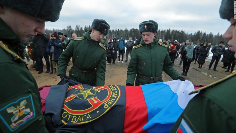 ウクライナで死亡したワグネル戦闘員の葬儀で、棺をロシア国旗で包む士官候補生ら/Igor Russak/Reuters