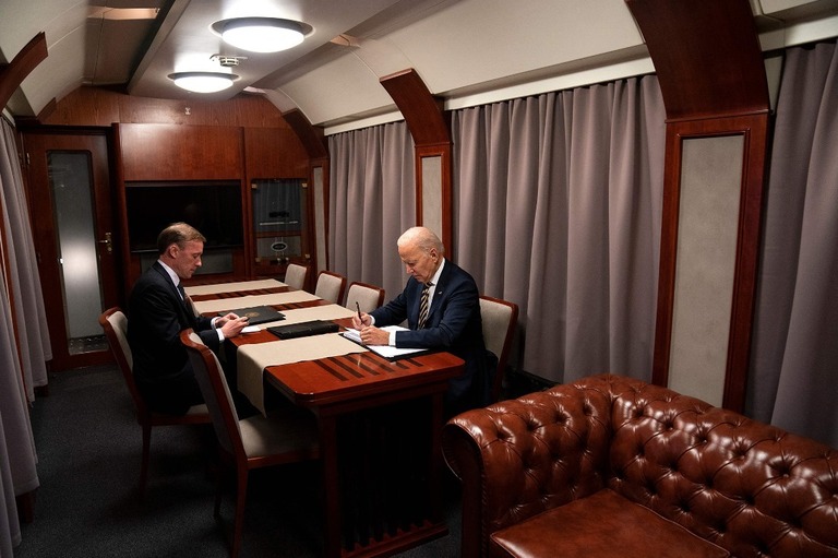 キーウの電撃訪問後、列車内でサリバン米大統領補佐官（左）と机に向かうバイデン氏/Evan Vucci/AFP/Getty Images