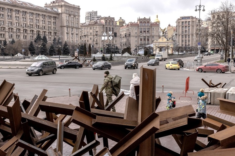 ウクライナ首都の広場に設置された対戦車用障害物の前を通り過ぎる人々＝２月２日撮影/Roman Pilipey/Getty Images