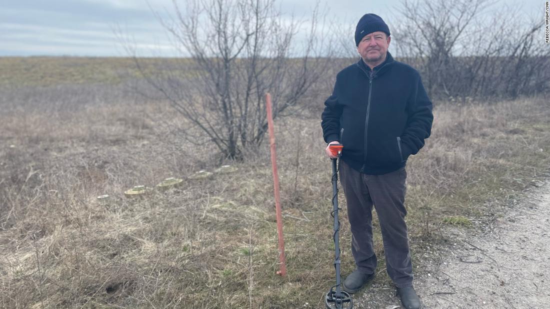 オレクサンドル・ハブリルクさん(69)と草むらに並ぶ対戦車地雷(写真左)。去作金属探知機で探り当てたという/Rebecca Wright/CNN