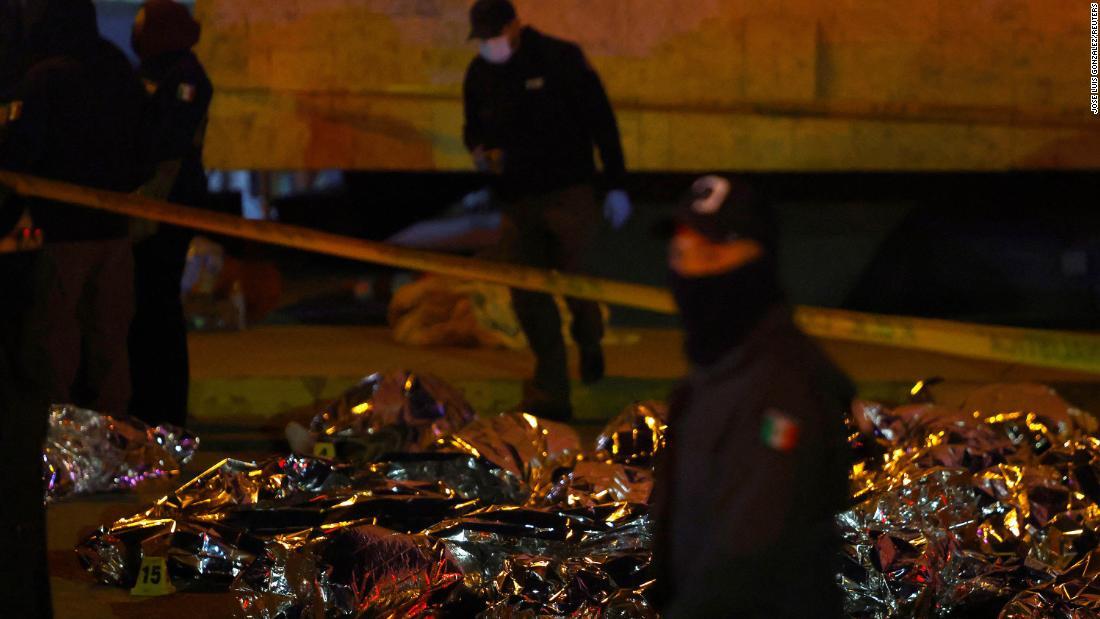 移民の遺体近くに立った救急隊員ら/Jose Luis Gonzalez/Reuters