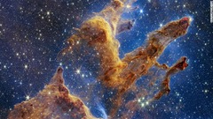 「創造の柱」の高解像度の画像。星間物質とガスでできた３本の柱が伸び、生まれたばかりの星々が輝きを放つ