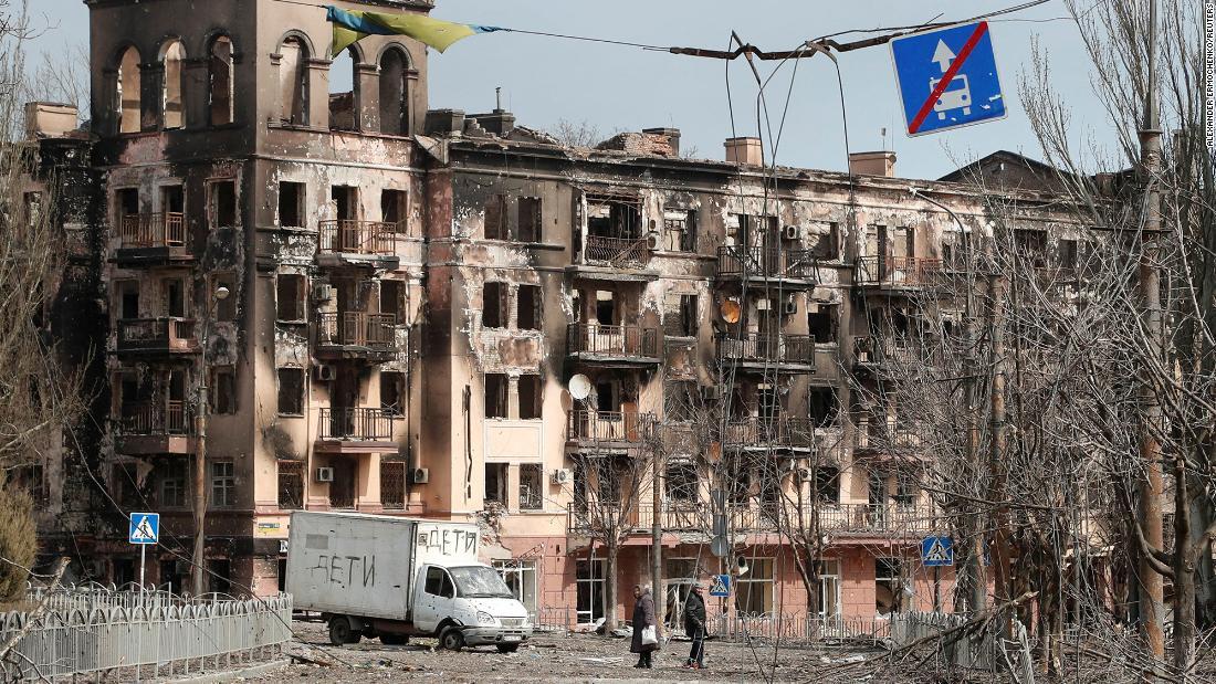 紛争で損傷したマリウポリの建物の前を歩く地元住民=2022年4月3日撮影/Alexander Ermochenko/Reuters