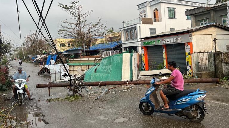 倒れた電柱を避けながらバイクで通る住民ら＝１５日、ミャンマーのラカイン州シットウェ/Sai Aung Main/AFP/Getty Images