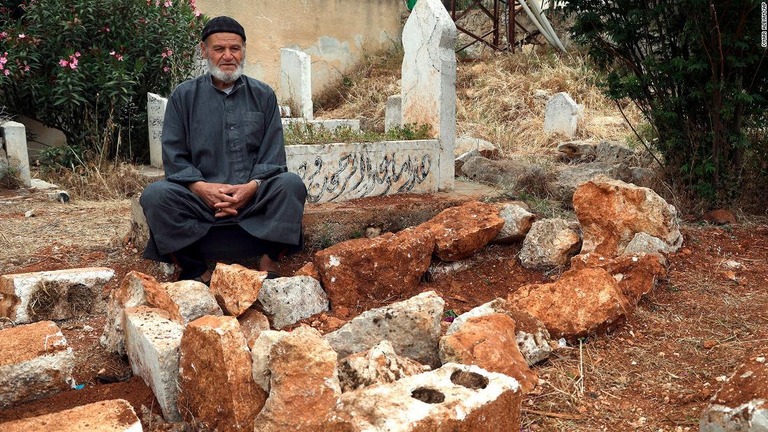 ルトフィ・ハッサン・メストさんの墓の横に座るモハマド・メストさん/Omar Albam/AP
