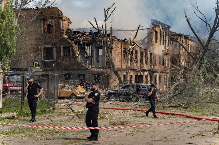 ロシアの攻撃によって損壊した病院の近くに立つ警官ら＝２６日、ウクライナ・ドニプロ州/Yurii Tynnyi/Global Images Ukraine/Getty Images