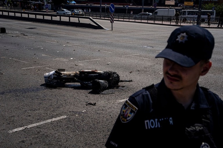 ウクライナ首都でロシア軍のロケット弾の破片を警備する警官/Evgeniy Maloletka/AP