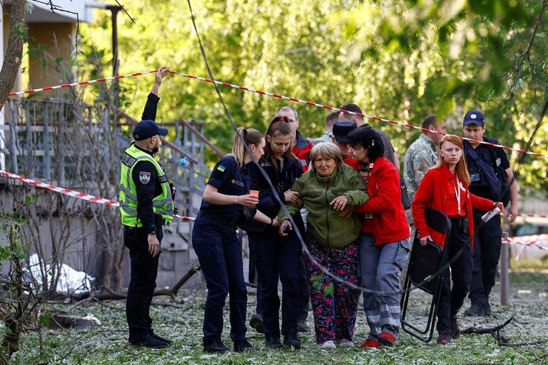 ウクライナ首都でのロシアのミサイル攻撃で死亡した人の家族に付き添う救急要員ら/Valentyn Ogirenko/Reuters