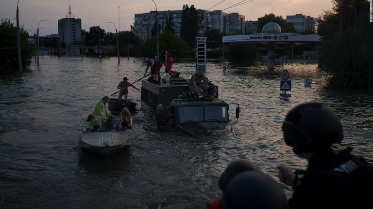 ダム決壊によって浸水した家屋から避難する人々＝６日、ウクライナ・ヘルソン州/Felipe Dana/AP