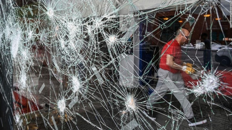 暴動でガラスが損傷した仏北部ルーべーの劇場施設の前を通りかかる自治体職員/Denis Charlet/AFP/Getty Images