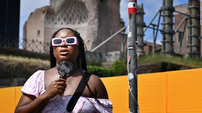 小型の扇風機で涼む女性＝１４日、イタリア・ローマ/Alberto Pizzoli/AFP/Getty Images