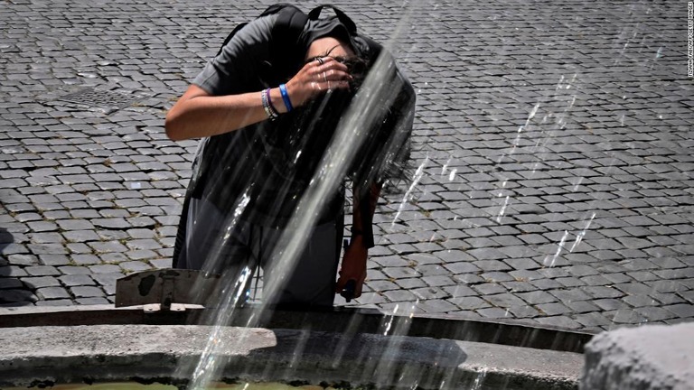 伊ローマで噴水の水を頭にかけて暑さをしのぐ少年/Tiziana Fabi/AFP/Getty Images