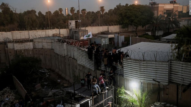 バグダッドにあるスウェーデン大使館近くのフェンスをよじ登るデモ参加者たち/Ahmed Saad/Reuters