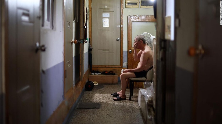 ソウルにある簡易宿泊所で、上半身裸になって扇風機の前に座る男性/Yonhap/EPA-EFE/Shutterstock