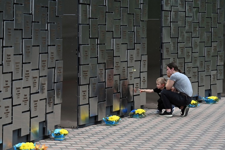 ウクライナ首都近郊のブチャでロシア軍に殺害された民間人を慰霊する施設を訪れる母子/Sergei Supinksky/AFP/Getty Images