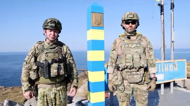 黄と青に彩られた国境標識の横に立つウクライナの国境警備隊/Serhiy Deineko Head of the Border Service/Reuters