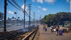 山火事が過ぎ去った後、荷物を持って移動する人々＝８月９日