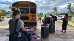 避難のためスクールバスで空港に到着した人々＝８月１０日