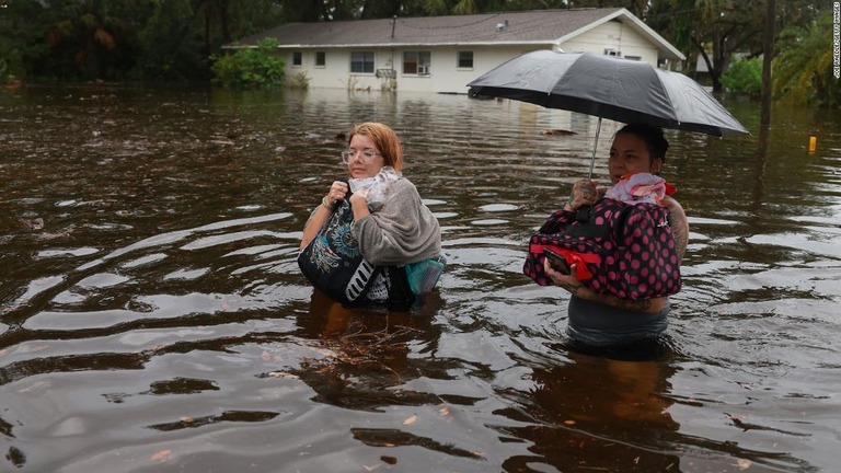 洪水で自宅から避難する親子＝３０日、フロリダ州ターポンスプリングス/Joe Raedle/Getty Images