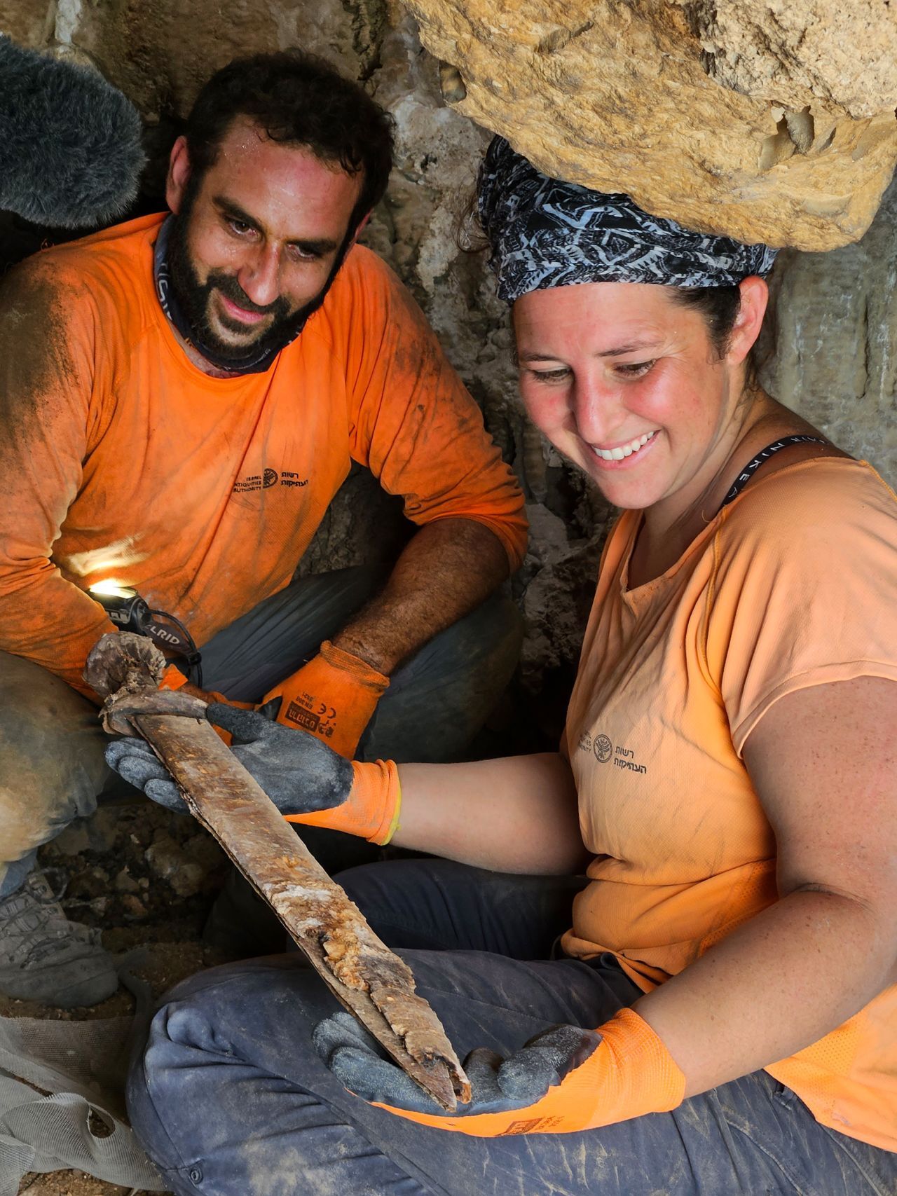 剣のうちの１本を手にする考古学者ら/Amir Ganor/Israel Antiquities Authority