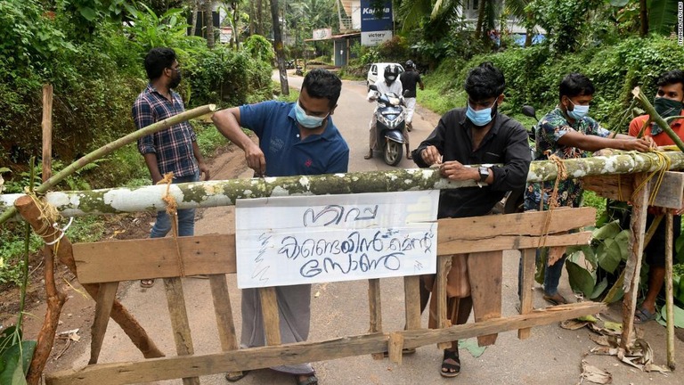 ニパウイルスの「封じ込めゾーン」の看板を掲げる住民たち＝１３日、インド・ケララ州/Stringer/Reuters