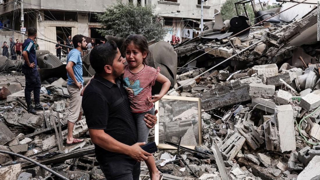泣き叫ぶ子供を抱く男性。イスラエルの空爆で破壊された建物の前で＝ガザ市/Mohammed Abed/AFP/Getty Images