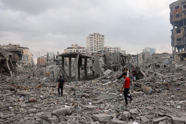 空爆を受けた現場を調べるパレスチナ人＝１０日、ガザ市リマル/Mohammed Abed/AFP/Getty Images