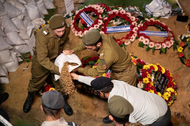 葬儀で墓に土をまくイスラエルの兵士＝１０日、エルサレム/Yuri Cortez/AFP/Getty Images