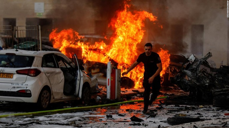 ガザからのロケット攻撃で火の手が上がる路上を走る男性/Amir Cohen/Reuters