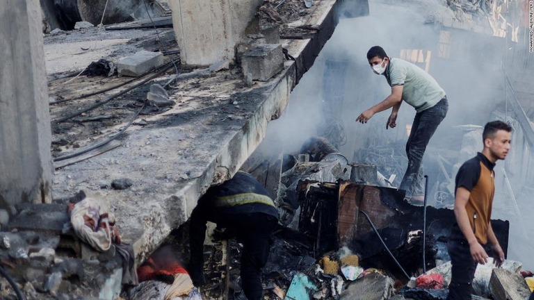 イスラエル軍の空爆によって破壊された建物のがれきの中で捜索を行うパレスチナの人々＝１４日、パレスチナ自治区ガザ地区/Mohammed Salem/Reuters