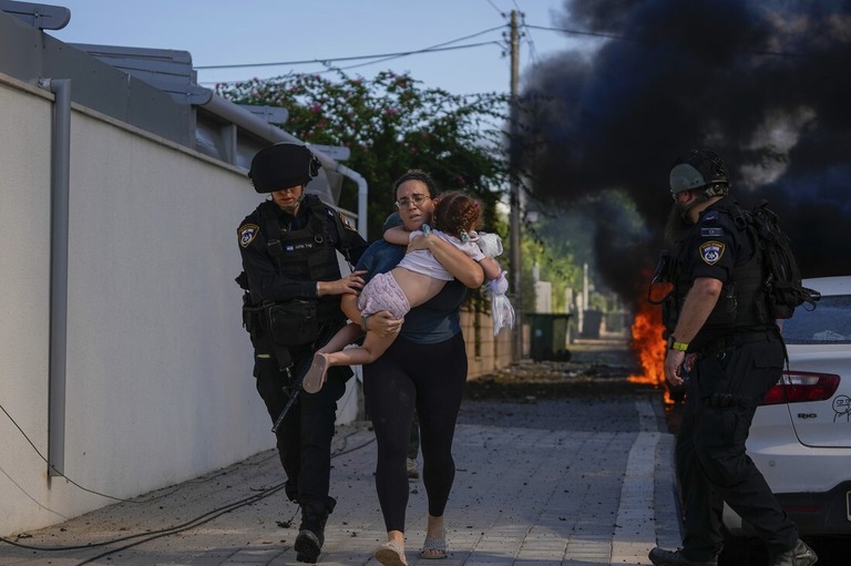 ガザ地区からのロケット攻撃を受けた現場から、警官が女性と子どもを避難させる様子＝７日、Tsafrir Abayov/AP
/Tsafrir Abayov/AP