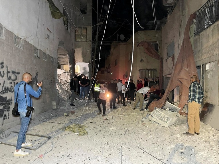 空爆を受けたモスク（イスラム教礼拝所）の被害状況を調べる人たち＝２２日、パレスチナ自治区ヨルダン川西岸地区/Mohammad Ateeq/Reuters