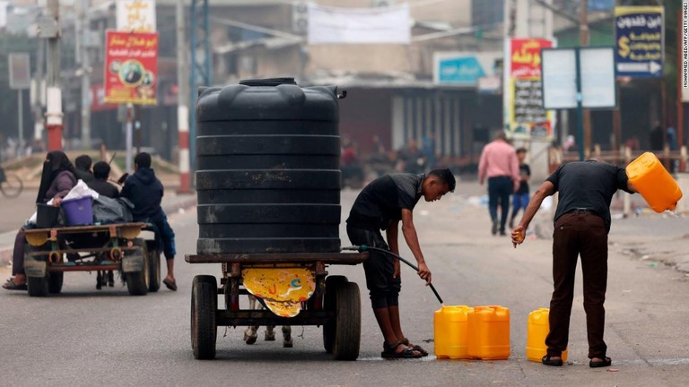 容器に水を入れる人たち＝２３日、パレスチナ自治区ガザ地区南部/Mohammed Abed/AFP/Getty Images