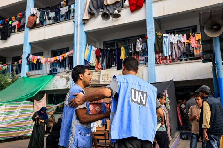 パレスチナ人の避難所となった教育施設の前で言葉を交わすＵＮＲＷＡの職員/Mahmud Hams/AFP/Getty Images