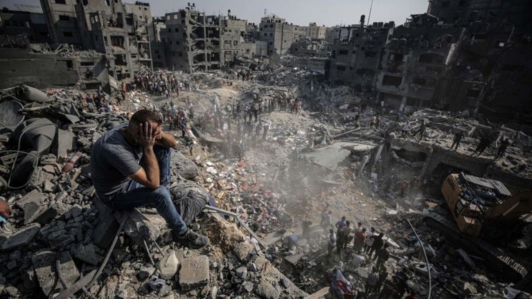 瓦礫と化したジャバリヤ難民キャンプで頭を抱えて座り込む男性/Ali Jadallah/Anadolu/Getty Images