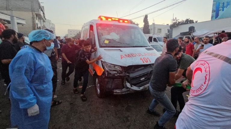 攻撃を受けて損傷した救急車を引いて移動させるパレスチナ人ら/Anas al-Shareef/Reuters