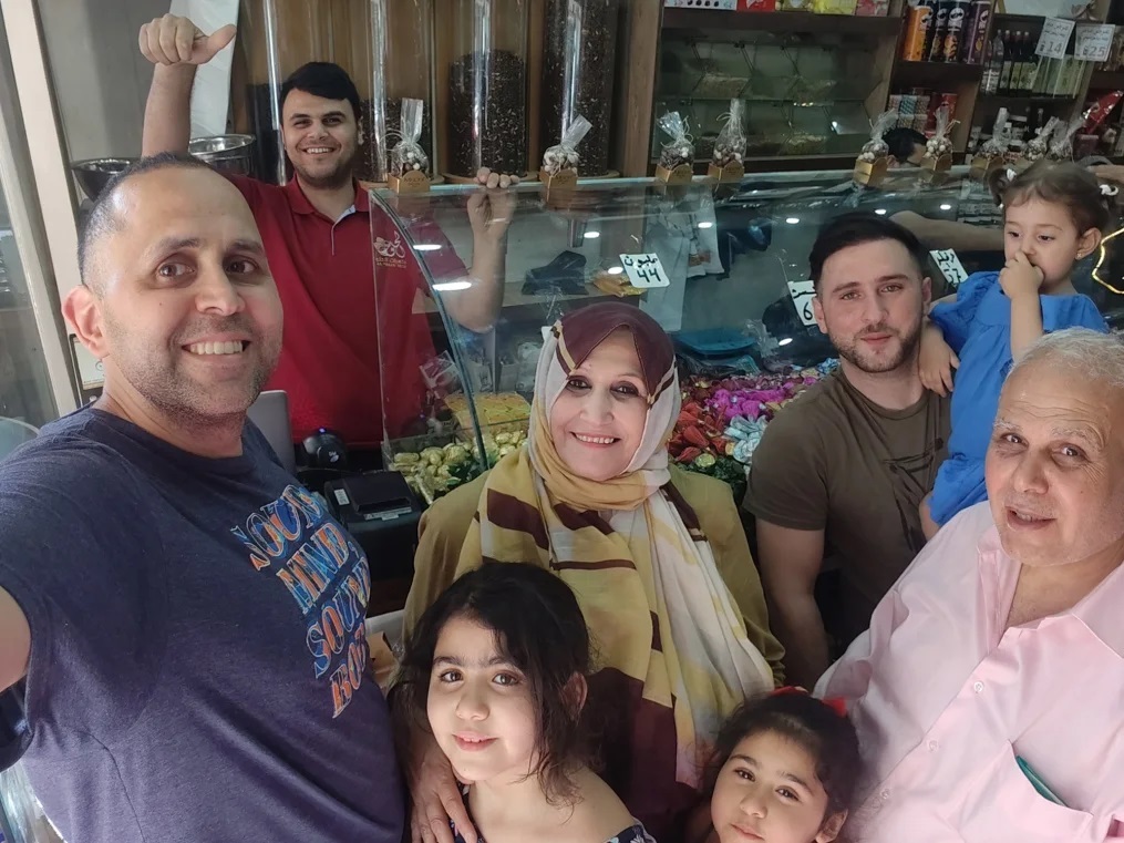今夏、故郷のガザを訪れ、家族と菓子店で記念撮影をする筆者のハニ・アルマドゥーン氏（左）/Hani Almadhoun