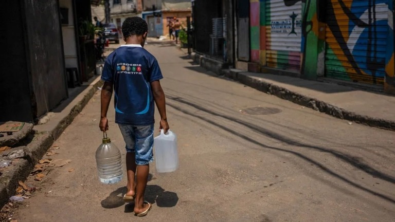 熱波に見舞われたブラジルのリオデジャネイロで、天然の湧き水から集めた水を運ぶ住民/Tercio Teixera/AFP/Getty Images