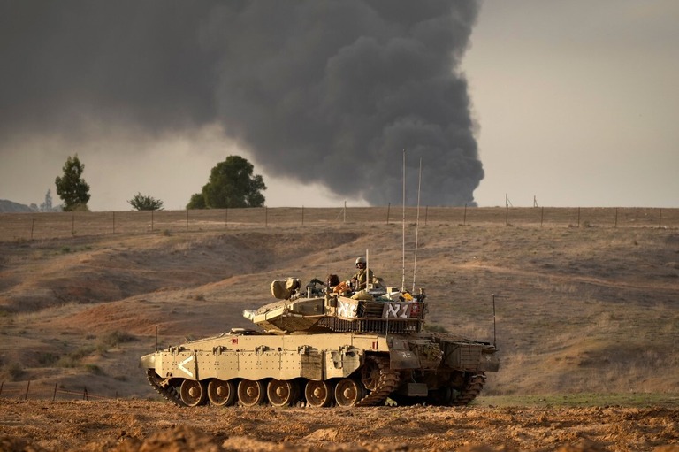 ガザ市の方向から立ち上る煙とガザ地区に向かうイスラエルの戦車＝２２日、イスラエル南部/Christopher Furlong/Getty Images