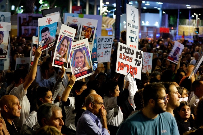 ポスターなどを持ちながら人質解放のニュースを待つ人々＝２５日、イスラエル・テルアビブ/Alexander Ermochenko/Reuters