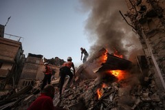 消火とともにがれきの中の生存者を捜索する人々＝１１月４日、パレスチナ自治区ガザ地区ハンユニス