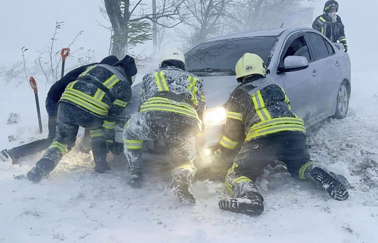 雪で立ち往生する車を押し出す救急隊員＝２７日、ウクライナ・オデーサ州/Ukrainian Emergency Service/AP