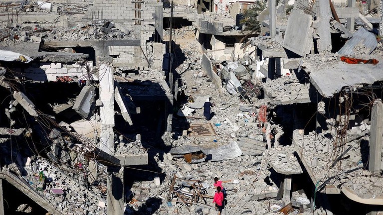 一時停戦中、イスラエルの空爆で破壊された家の跡を歩く少女/Mohammed Salem/Reuters