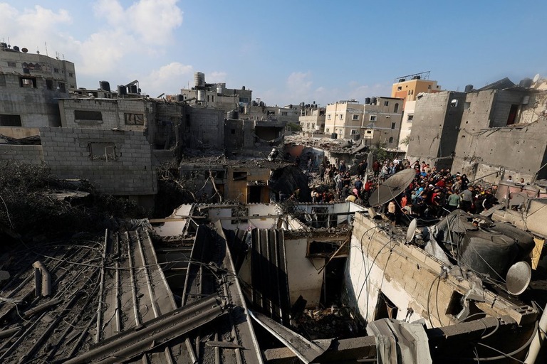 ガザ地区ハンユニスで、イスラエル軍による空爆の被害を確認するパレスチナ人ら/Mohammed Salem/Reuters