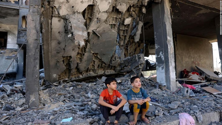 損壊した建物の前に座る子どもたち/MOHAMMED ABED/AFP/AFP via Getty Images