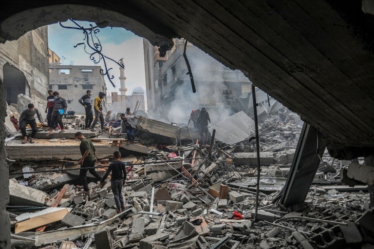 ガザ地区南部ハンユニスで空爆により破壊された建物の跡を調べる人々＝５日/Ahmad Hasaballah/Getty Images