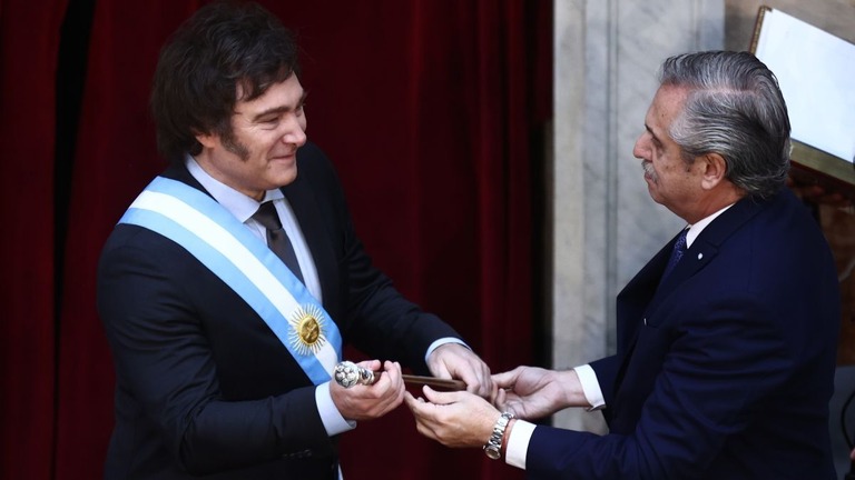 就任式でミレイ氏が前大統領のフェルナンデス氏から大統領の杖を受け取る/Tomas Cuesta/Getty Images