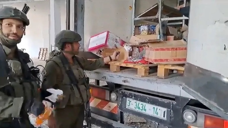 トラックの中の食料品に火を付けようとするイスラエル軍の兵士/Obtained by CNN
