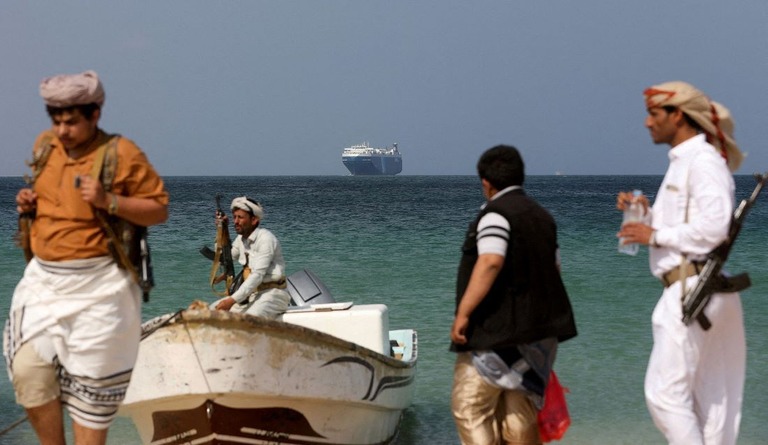 武装した男性らが立つ海岸の後ろには、イエメンの反政府武装組織フーシに拿捕（だほ）された貨物船「ギャラクシー・リーダー」が見える＝１２月５日/Khaled Abdullah/Reuters